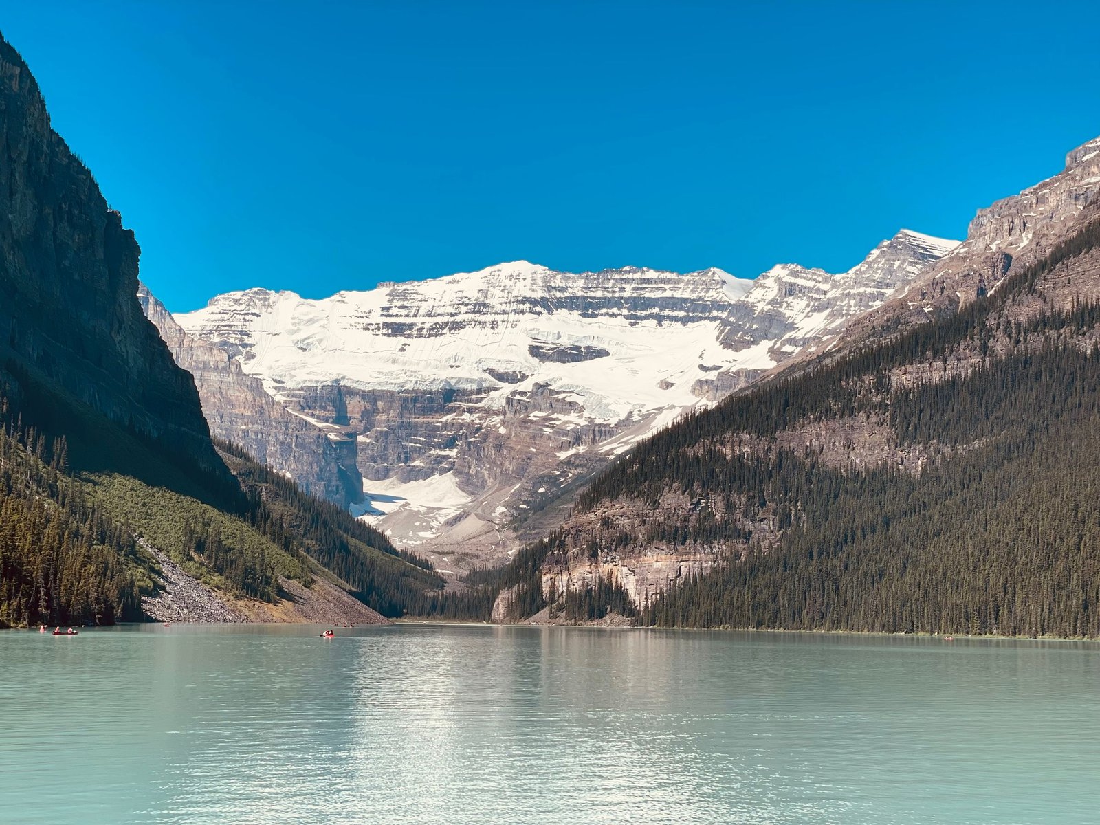 Beautiful view of Lake Louise with snow-capped Rocky Mountains under clear blue skies.